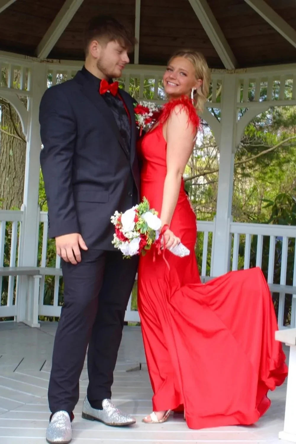 Red V-neck mermaid prom dress featuring luxury diamond straps, feather accents, and an open back.