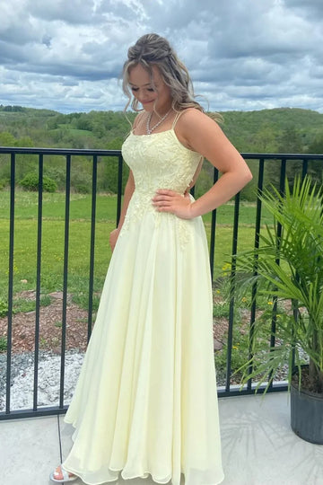 Flowy yellow chiffon A-line prom dress featuring delicate lace appliques and a double strap back design.