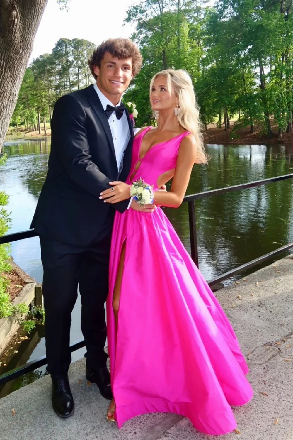 Vibrant hot pink formal gown featuring a plunging V-neckline, waist cut-outs, and a high leg slit.