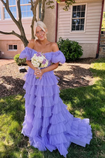 Lilac A-line tulle gown featuring an off-the-shoulder neckline, illusion bodice detail, and a voluminous tiered dress.