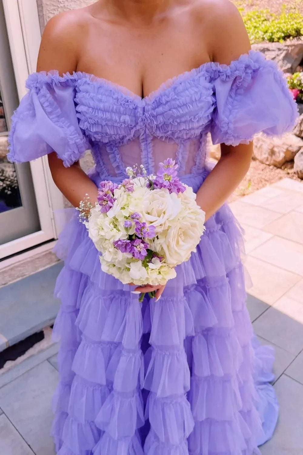 Lilac A-line tulle gown featuring an off-the-shoulder neckline, illusion bodice detail, and a voluminous tiered dress.