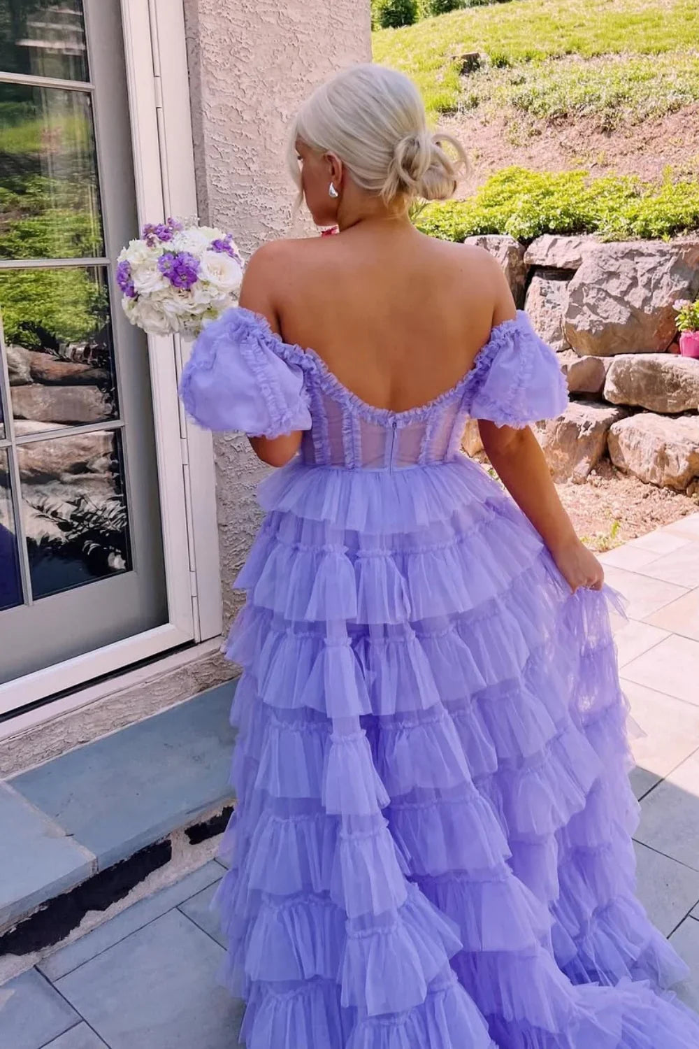 Lilac A-line tulle gown featuring an off-the-shoulder neckline, illusion bodice detail, and a voluminous tiered dress.
