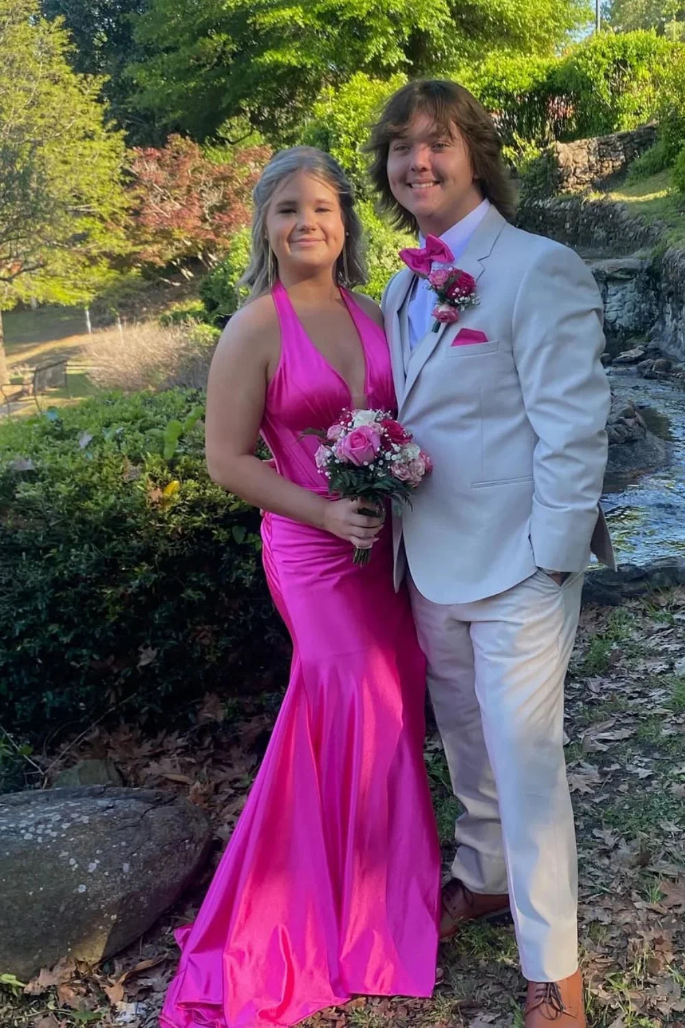 Bold fuchsia mermaid prom dress featuring a halter plunging V-neckline and elegant ruching throughout the bodice and skirt.