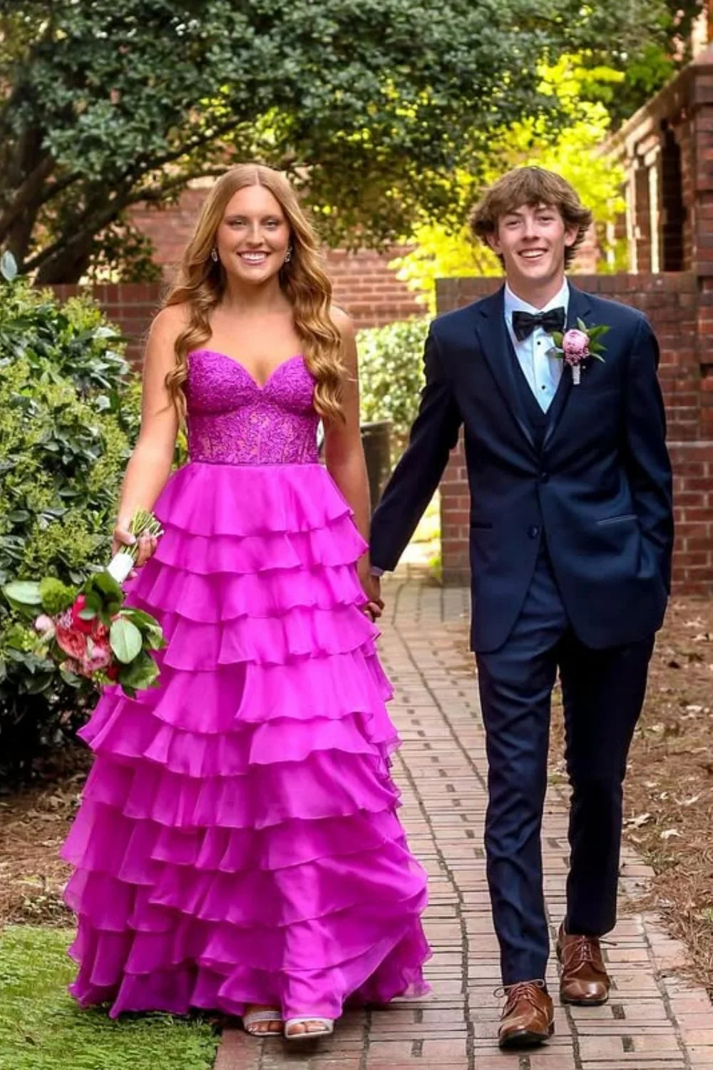 Purple A-line evening gown featuring a strapless neckline, delicate lace appliques, a tiered skirt, and a corset-style lace-up back.
