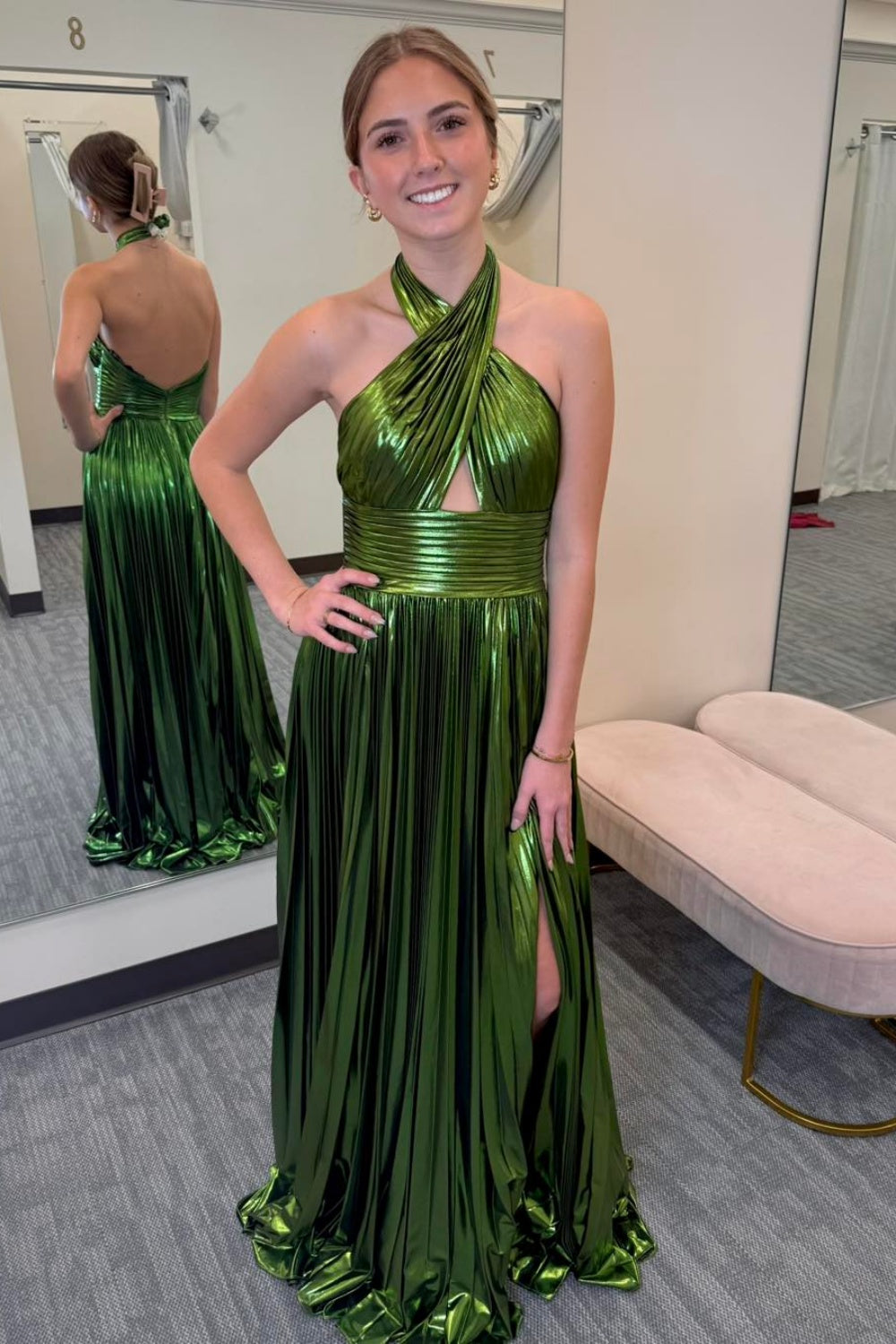 Metallic green halter A-line pleated formal dress with leg slit and open back.