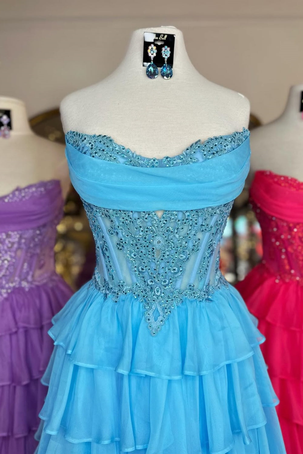A-line tiered chiffon gown featuring a cowl neck and beaded lace appliques.