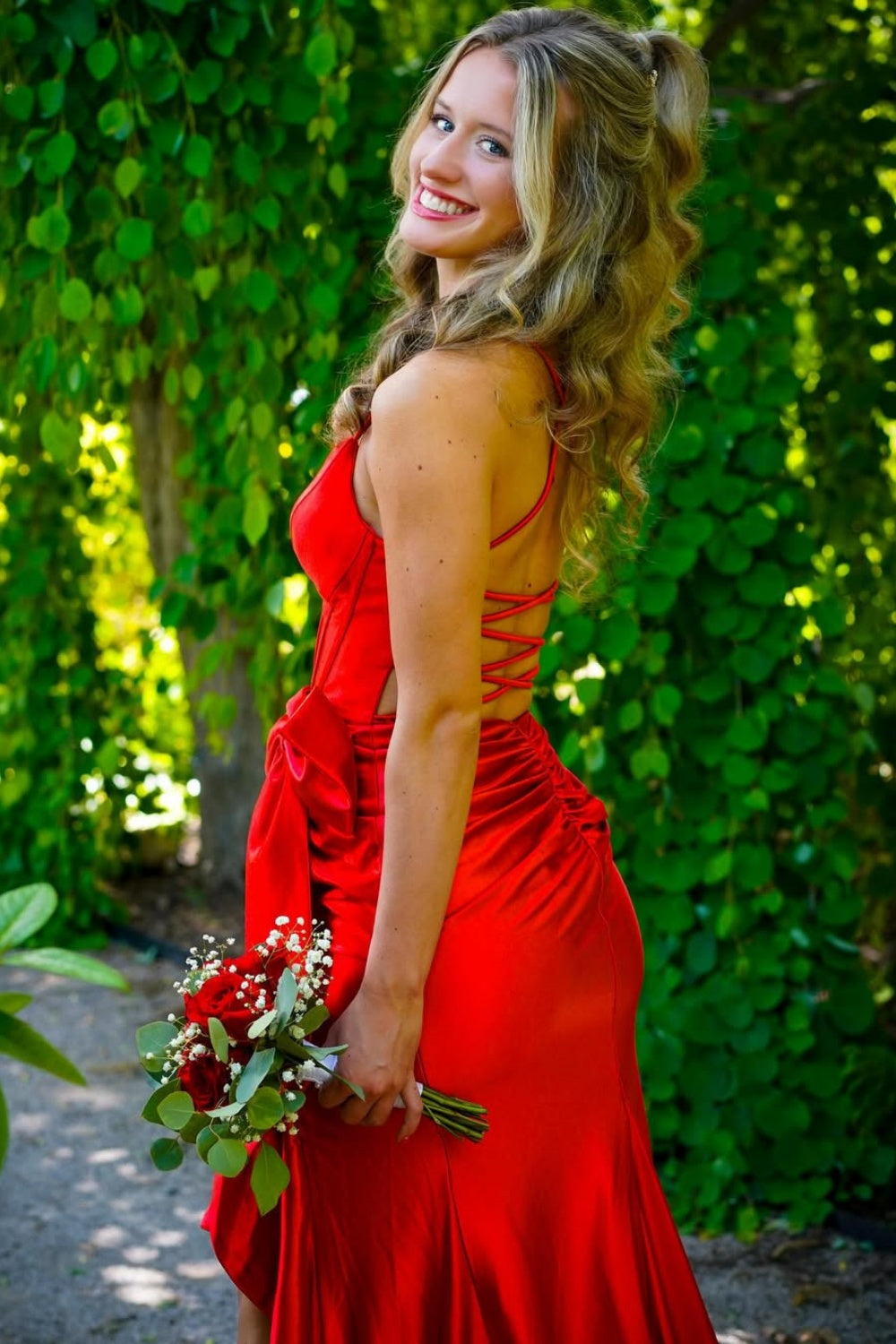 Red mermaid prom dress with a strapless bow neckline and ruched tie-back detail.