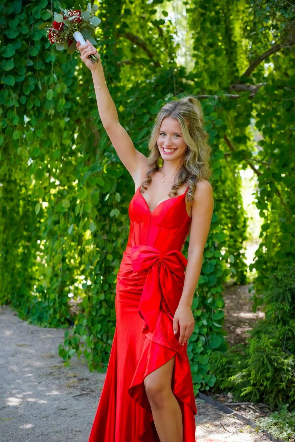 Red mermaid prom dress with a strapless bow neckline and ruched tie-back detail.