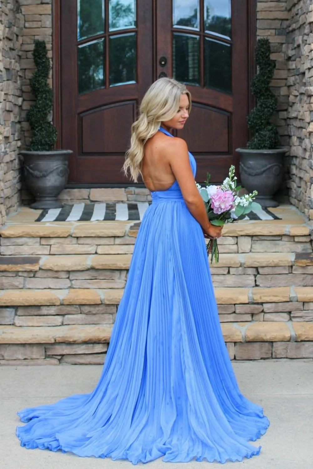 Halter neck pleated chiffon A-line gown with open back and side slit.