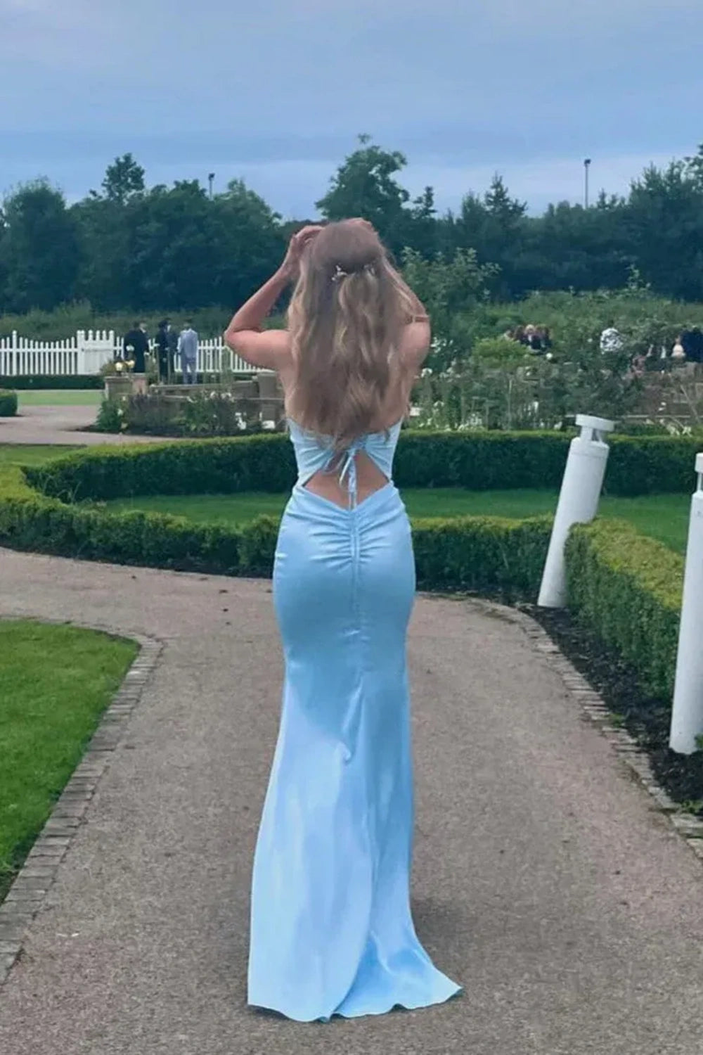 Light blue mermaid prom dress with spaghetti straps, ruched detailing, and a tie-back closure.