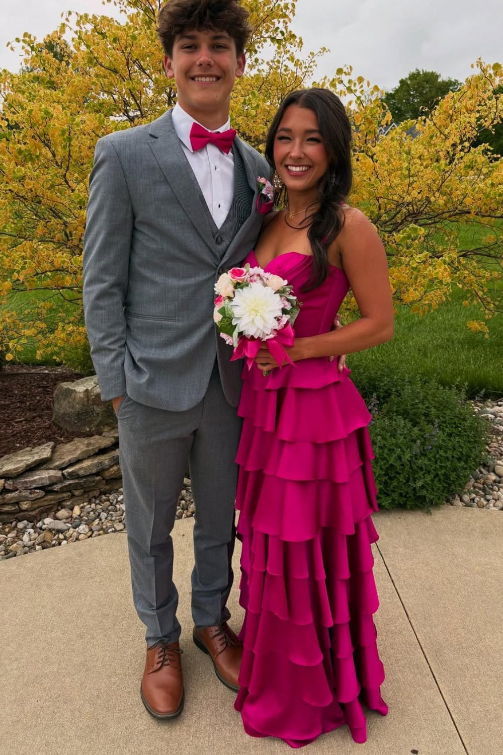Fuchsia A-line formal prom dress with spaghetti straps, ruffled skirt, and side slit.