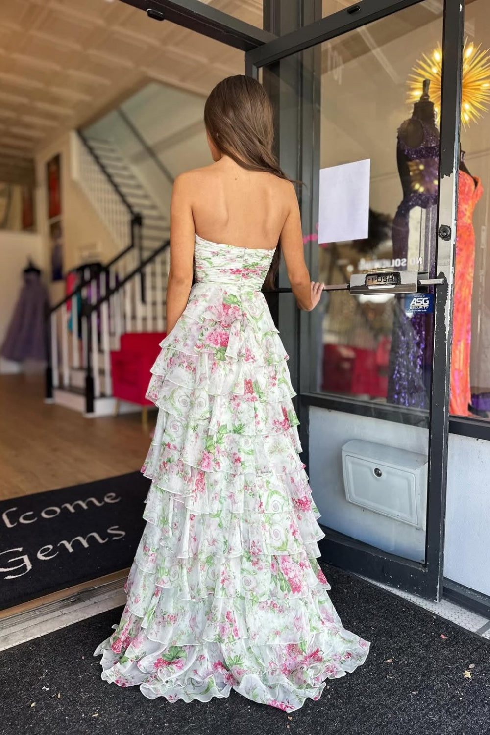 Floral print chiffon A-line prom dress featuring ruffles, a side slit, and a bow front detail.