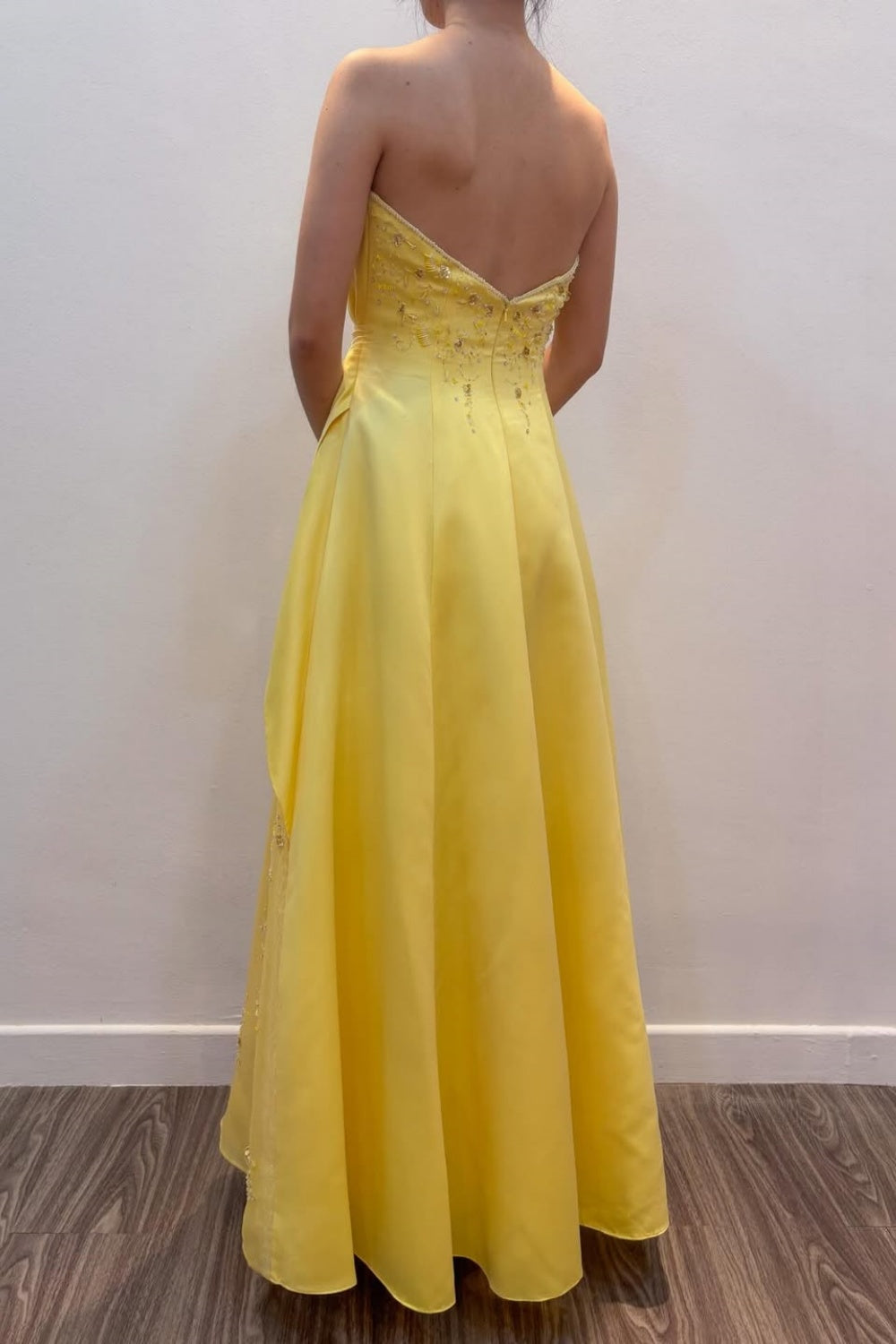 Strapless yellow long formal dress featuring 3D-flower appliques, intricate beading, and an asymmetrical skirt.