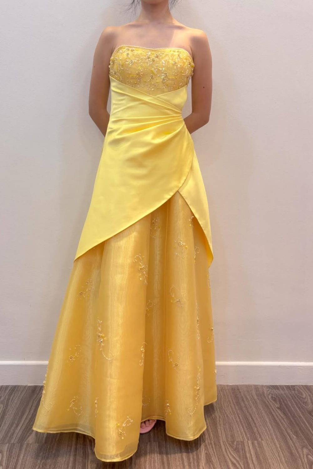 Strapless yellow long formal dress featuring 3D-flower appliques, intricate beading, and an asymmetrical skirt.