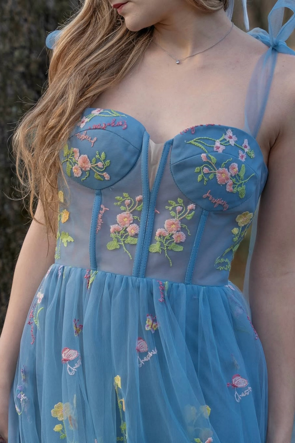 Blue A-line tulle prom dress with flower appliques and bow straps.