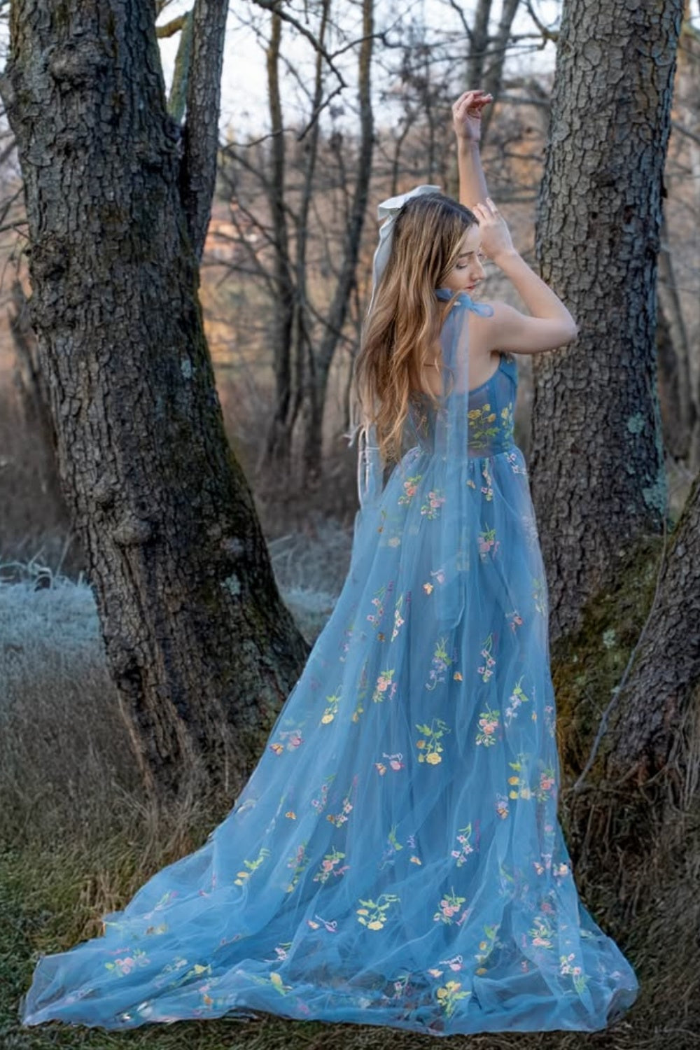 Blue A-line tulle prom dress with flower appliques and bow straps.
