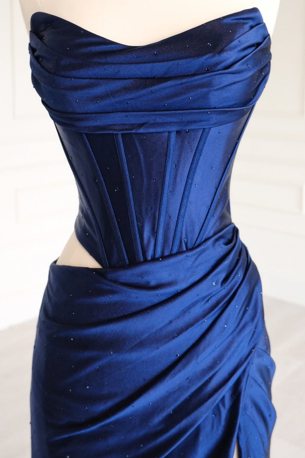 Navy blue strapless beaded formal dress with ruched cut-out and leg slit.