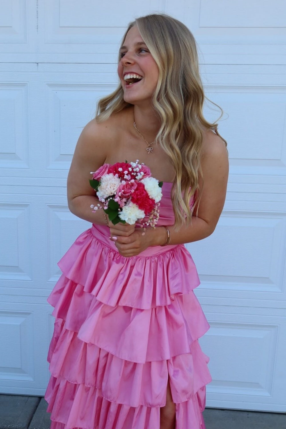 Pink strapless A-line tiered prom gown with ruched bodice and side slit.