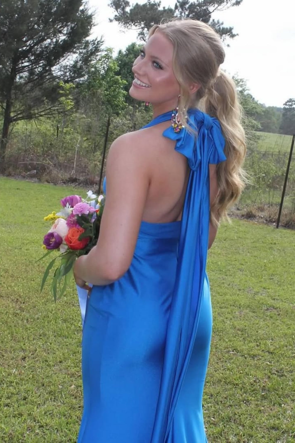 Satin halter mermaid prom dress featuring a large back bow and open back.
