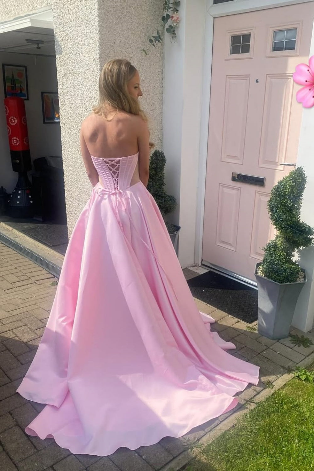 Light pink A-line satin prom gown featuring a sweetheart neckline, beaded bodice, and side cut-out details.