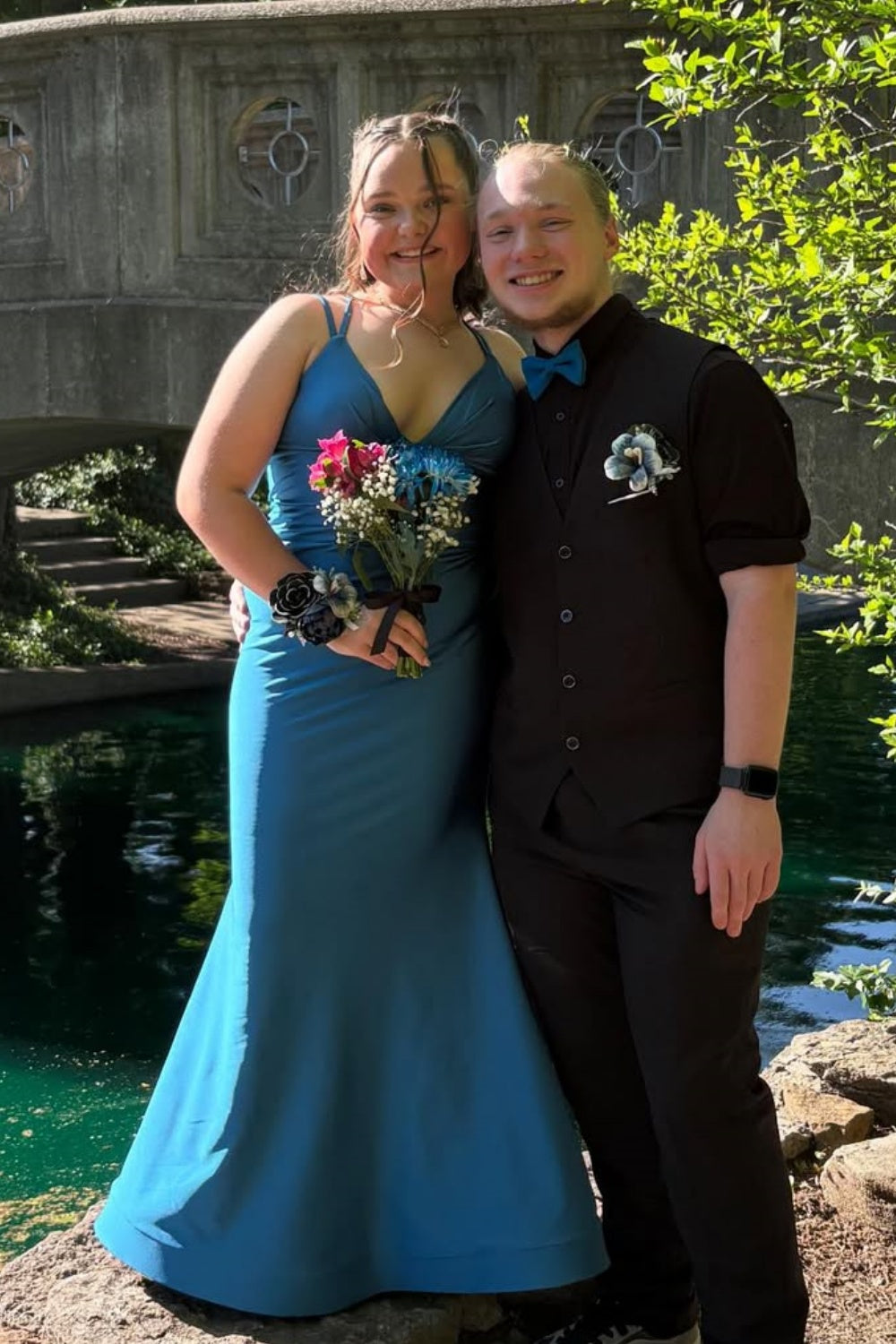 Blue mermaid prom dress featuring double spaghetti straps, a ruched plunging V-neckline, and a classic lace-up corset back.