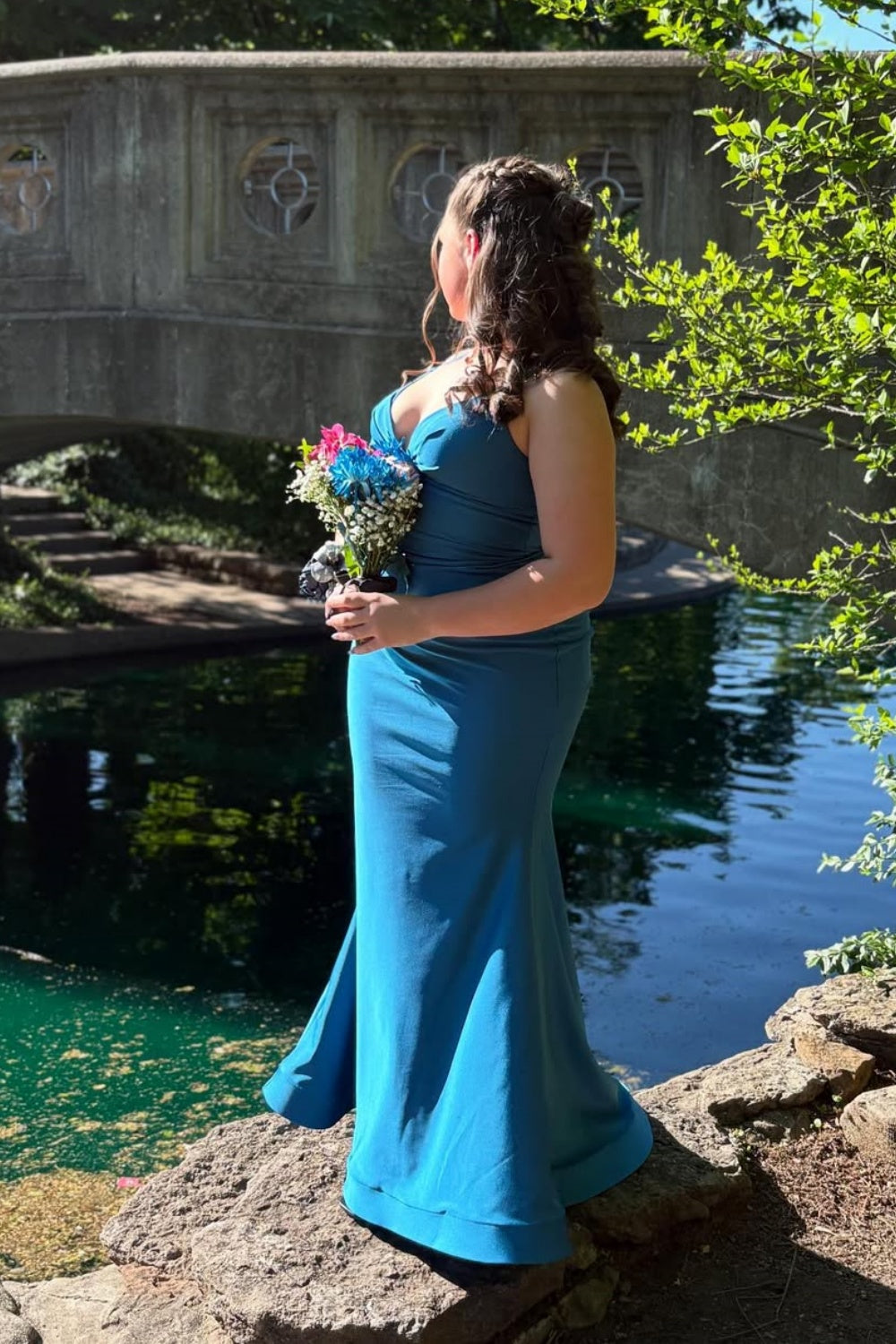 Blue mermaid prom dress featuring double spaghetti straps, a ruched plunging V-neckline, and a classic lace-up corset back.