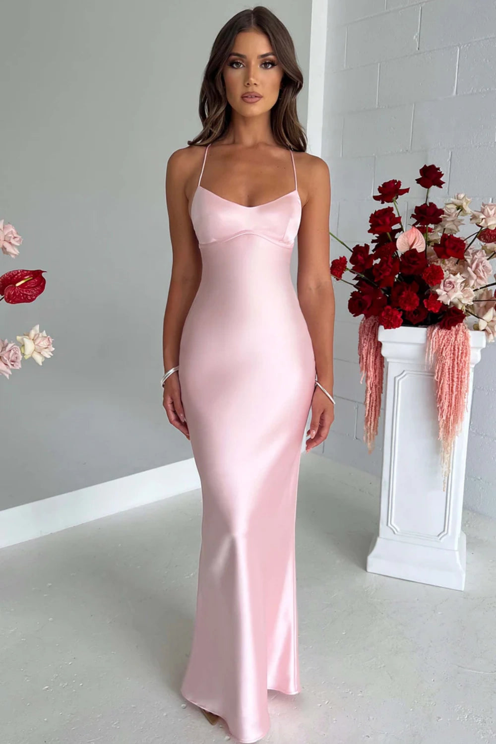 Fitted long pink formal prom dress with delicate spaghetti straps and a criss-cross lace-up back.