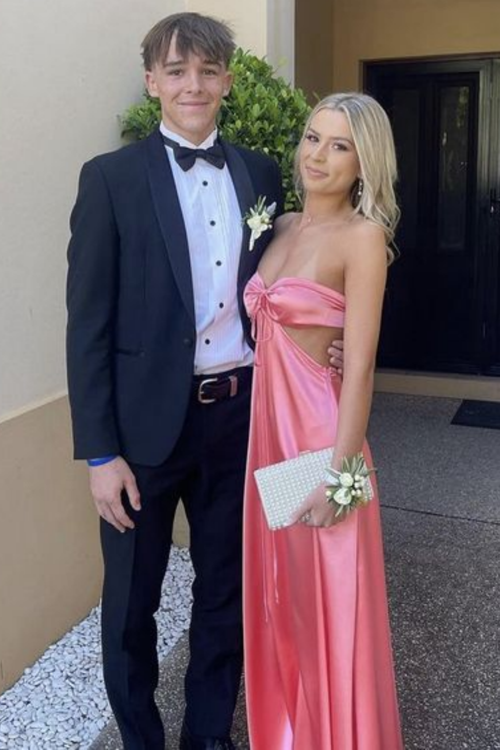Blush pink A-line satin prom dress featuring a strapless neckline, side cut-outs, and a dramatic bow-back design.