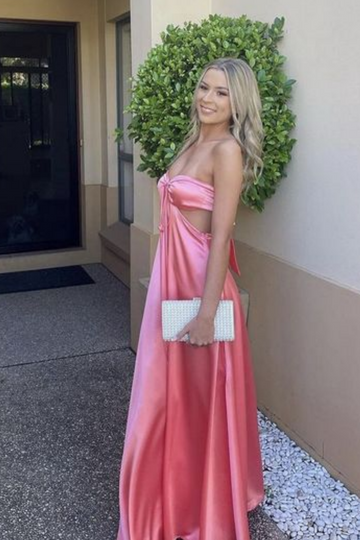 Blush pink A-line satin prom dress featuring a strapless neckline, side cut-outs, and a dramatic bow-back design.