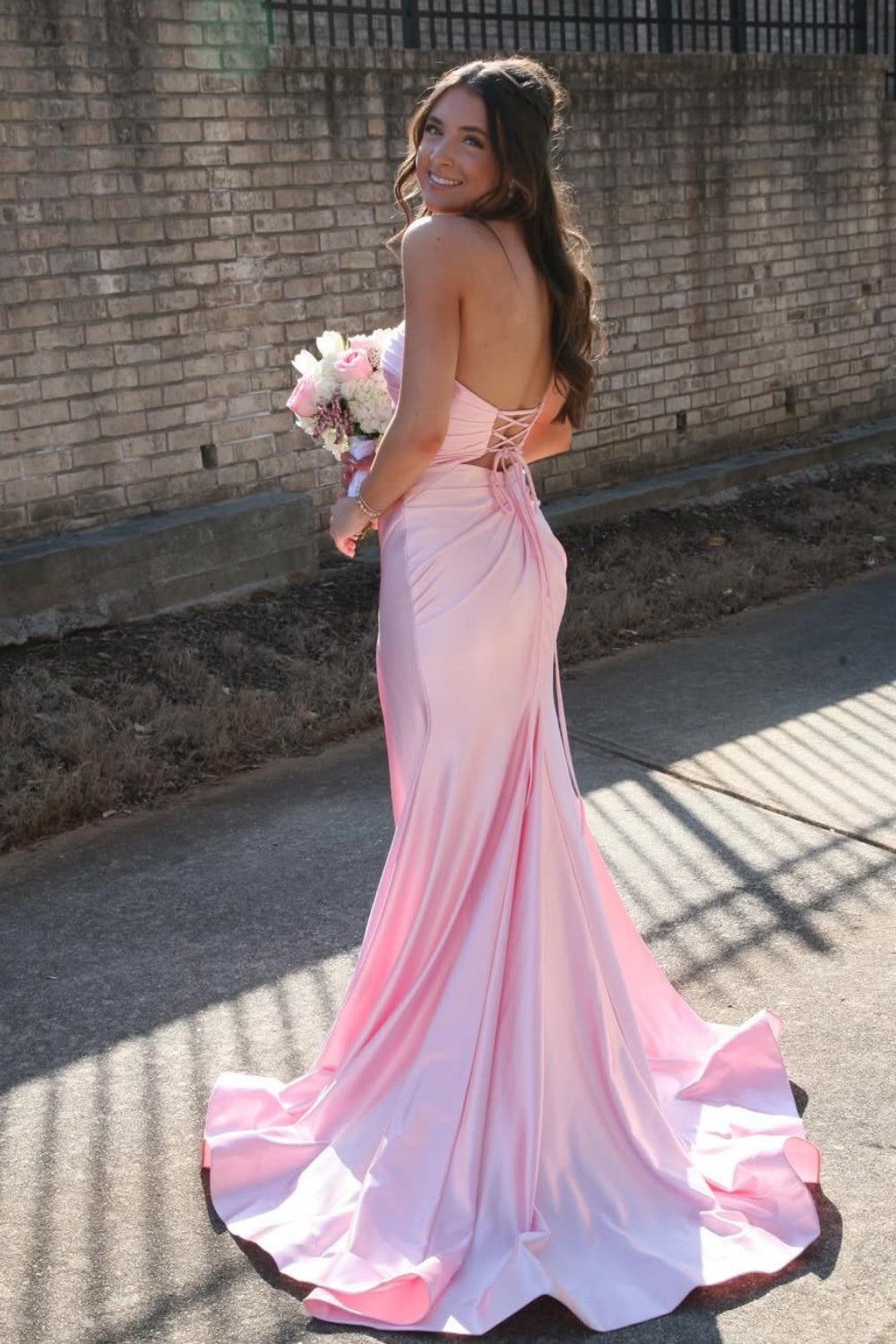 Strapless pink ruched mermaid gown with keyhole cutout and side slit.