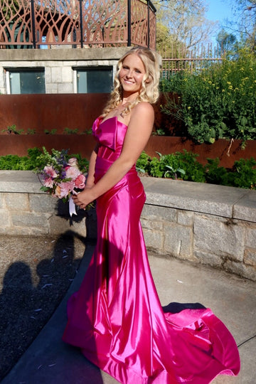 Fuchsia mermaid prom dress with ruching, keyhole detail, and a large bow.