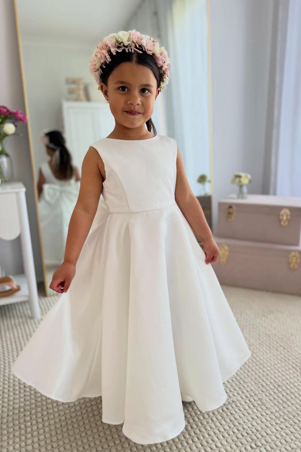 White sleeveless satin A-line flower girl dress with a large back bow.