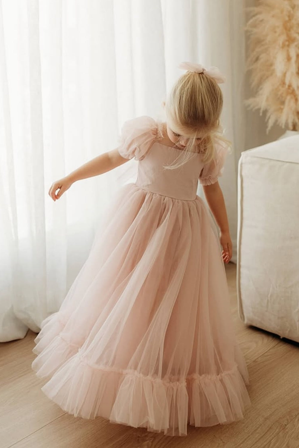 Pink A-line tulle flower girl dress with cap sleeves and back bow.