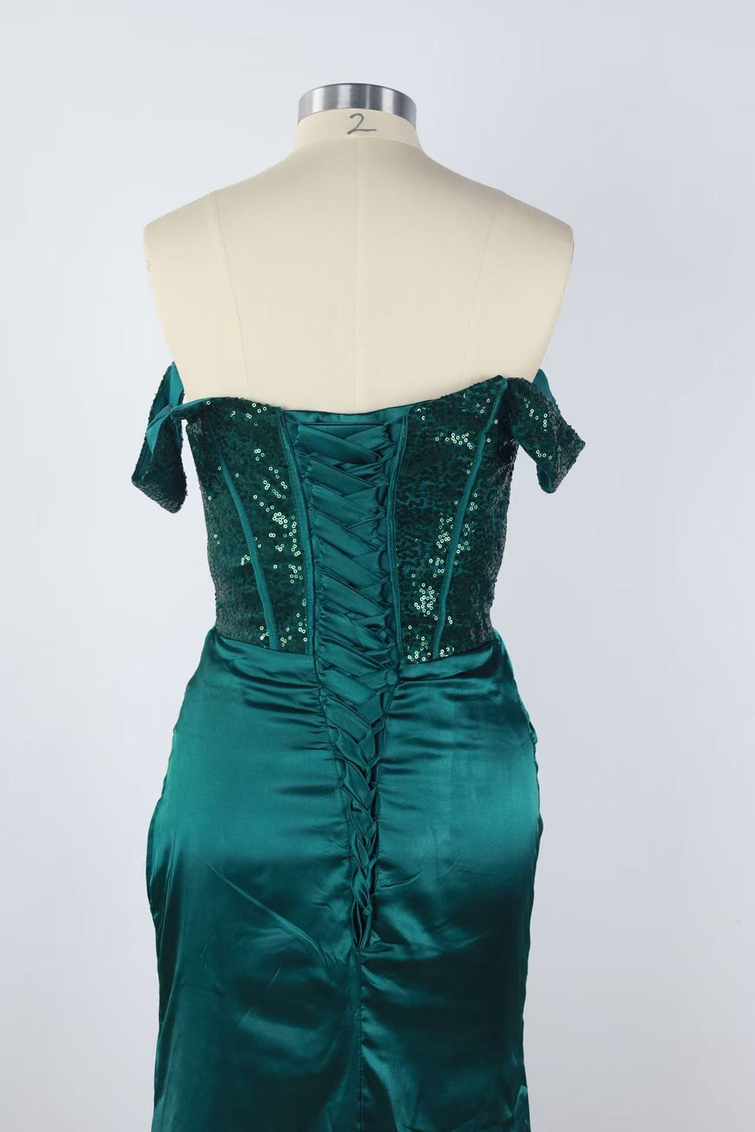 Off-the-shoulder green lace gown with side slit and lace-up back.
