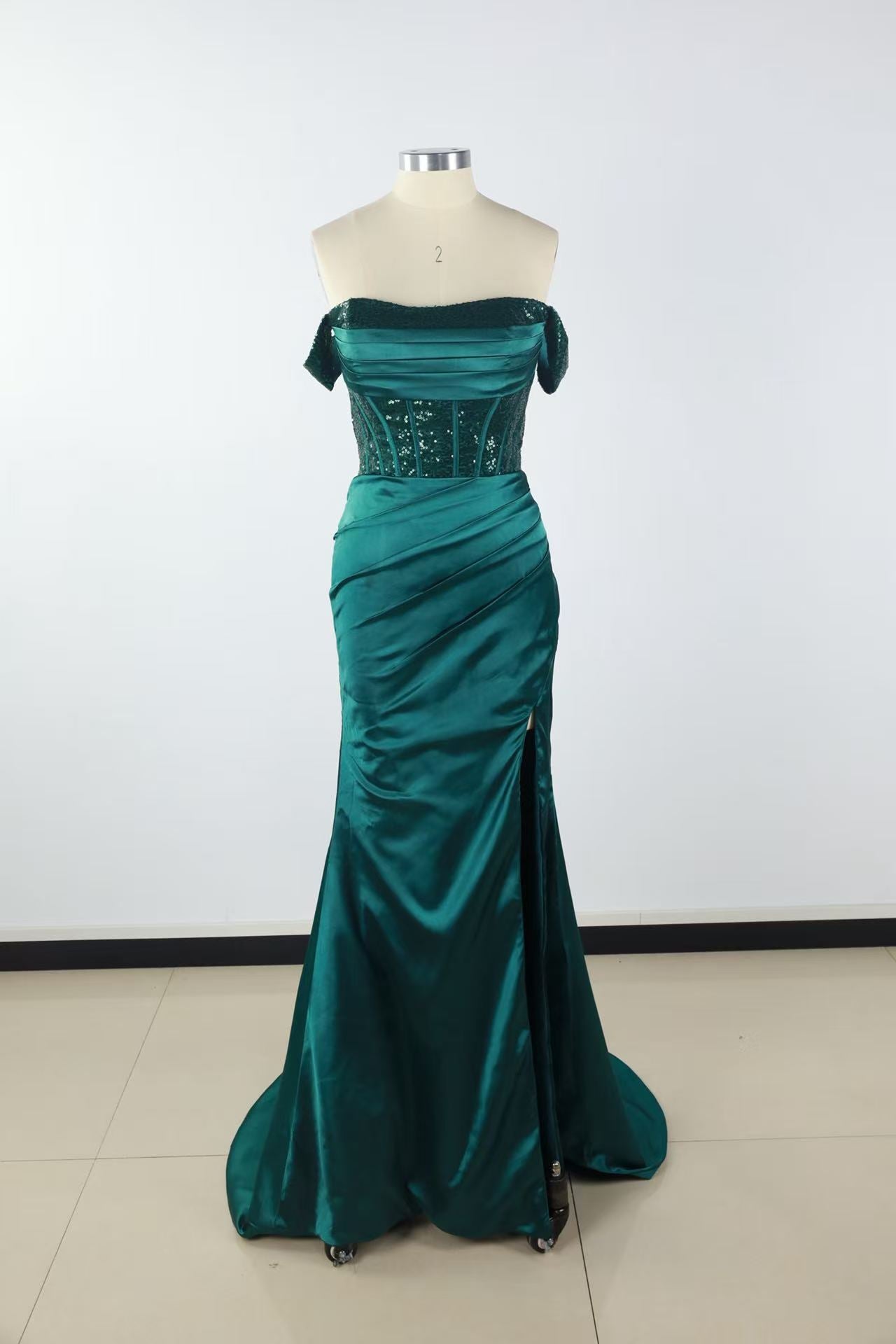 Off-the-shoulder green lace gown with side slit and lace-up back.